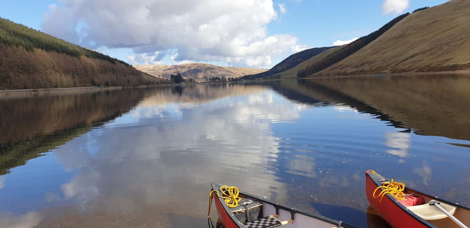 Canoes on a reflective mountain reservoir, tranquil lake scenery