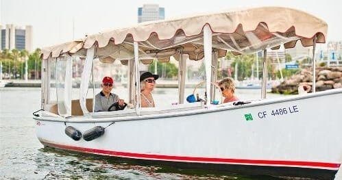 Shaded harbor boat ride near Newport Beach piers with tourists