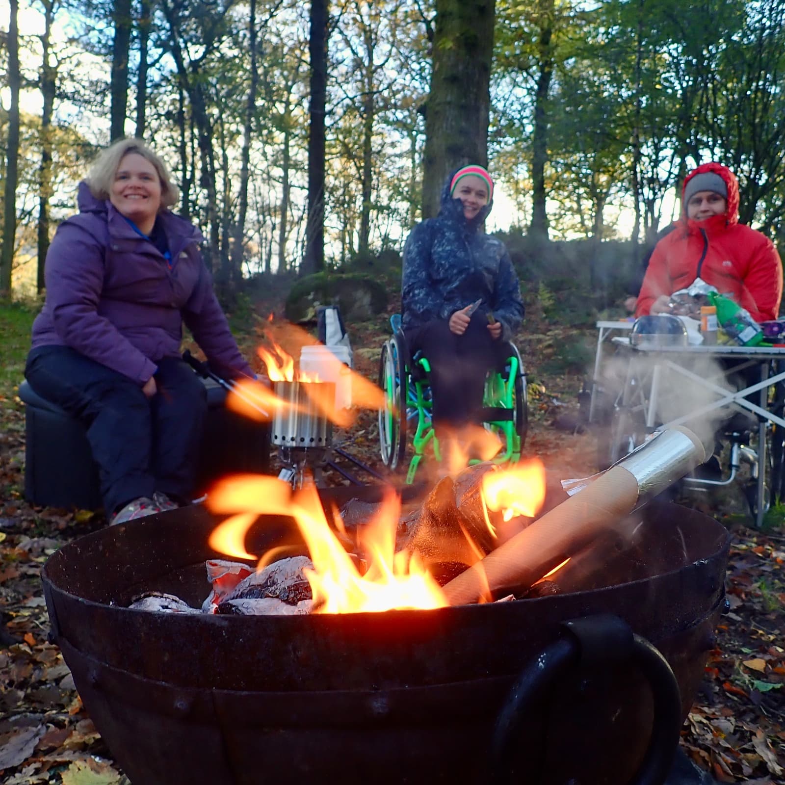 Group gathered around a woodland campfire enjoying outdoor fire