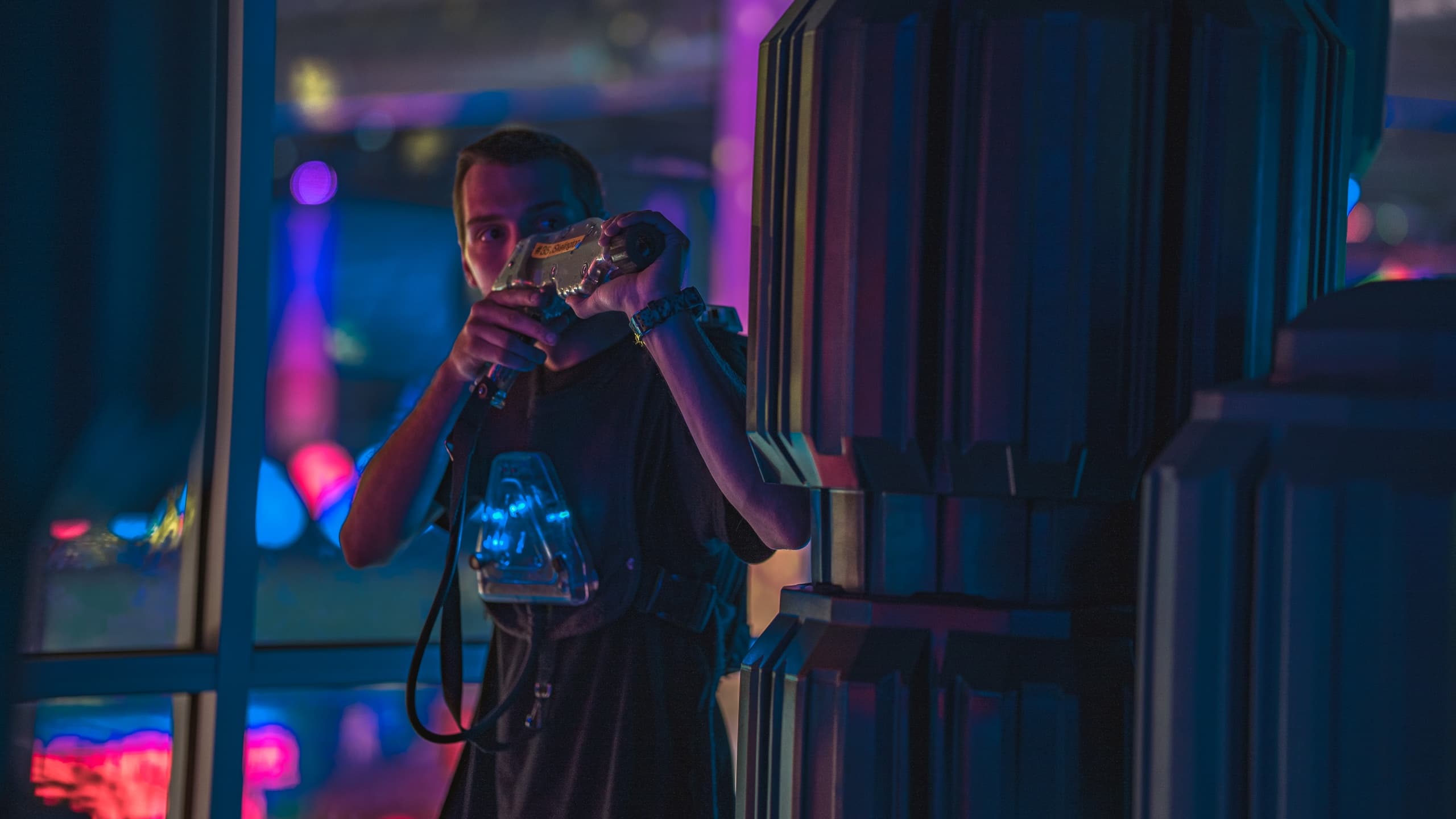 Person photographing neon-lit indoor entertainment arena at night