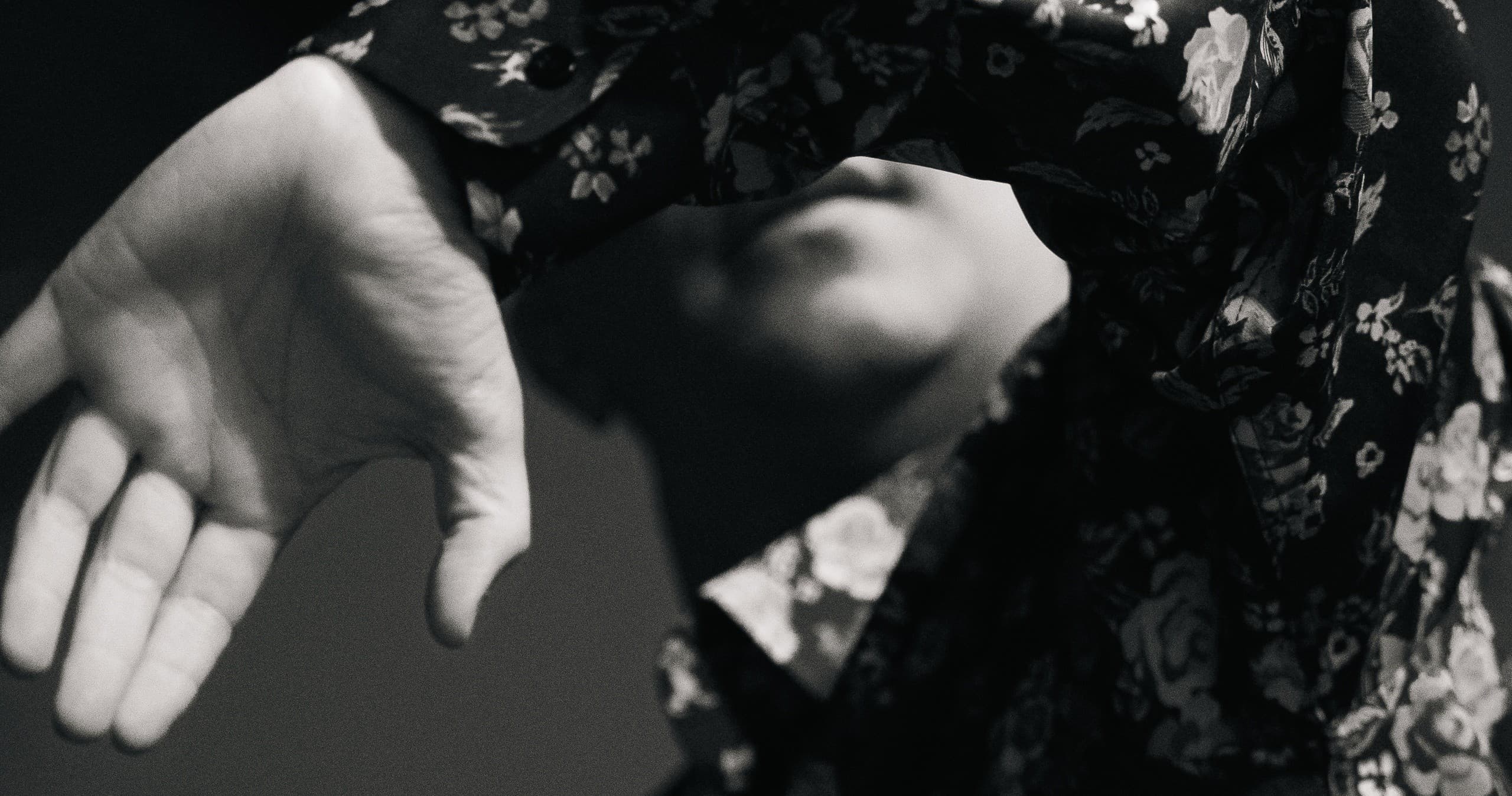 Studio black-and-white portrait of person shielding face, moody