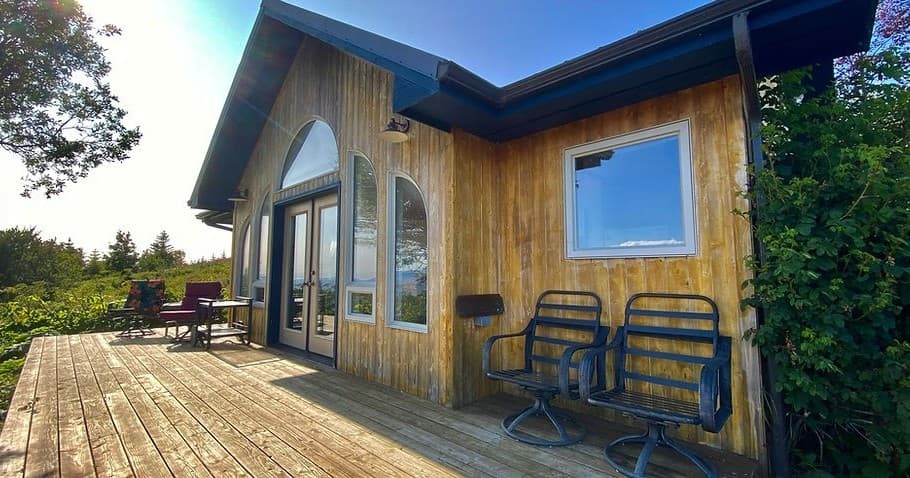 Cozy wooden fishing cabin with ocean-view deck and chairs