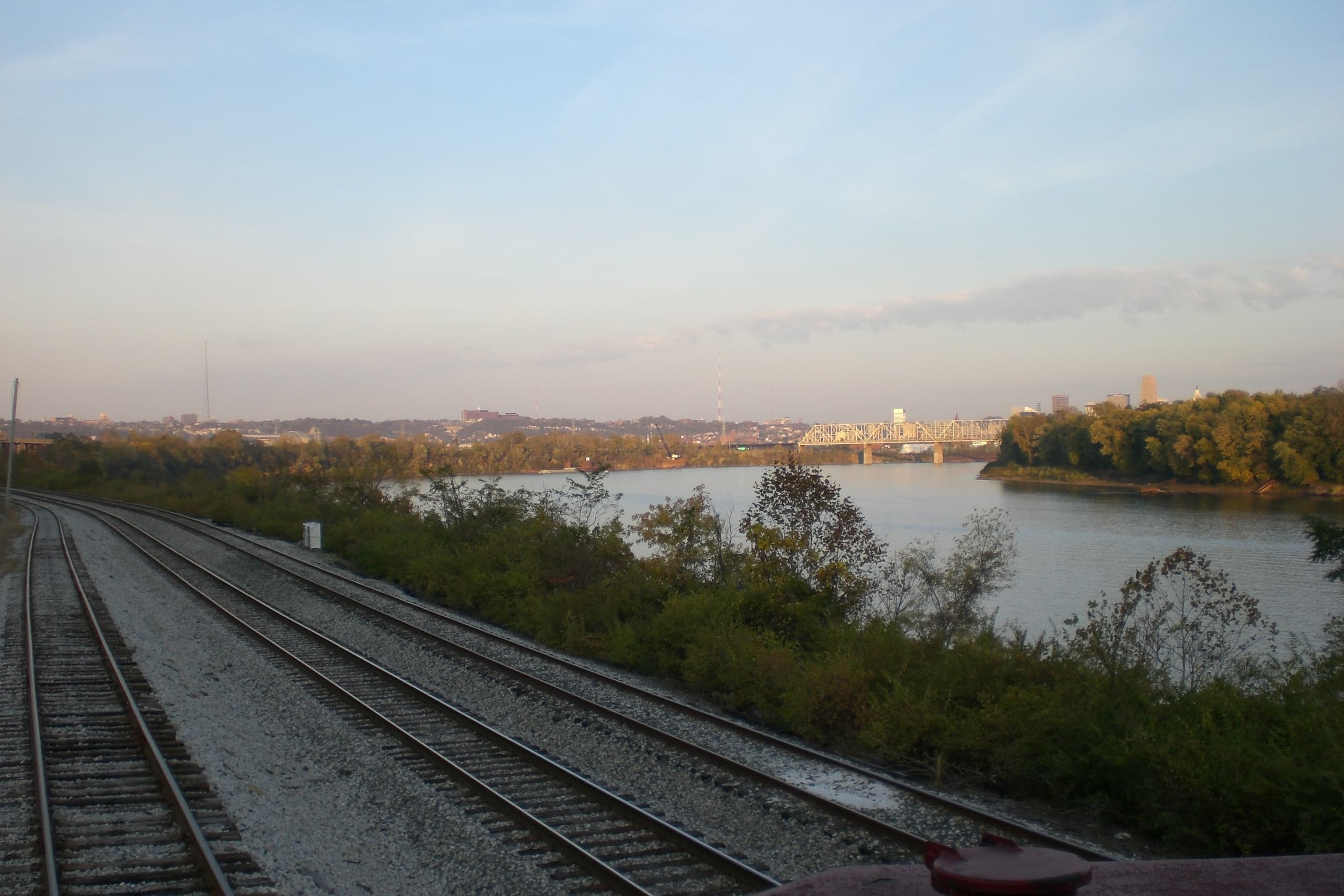 Rail tracks along river with city skyline at sunset