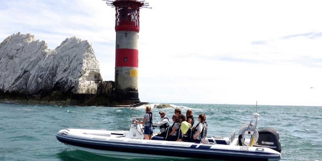 RIB tour cruising near rocky lighthouse and sea cliffs