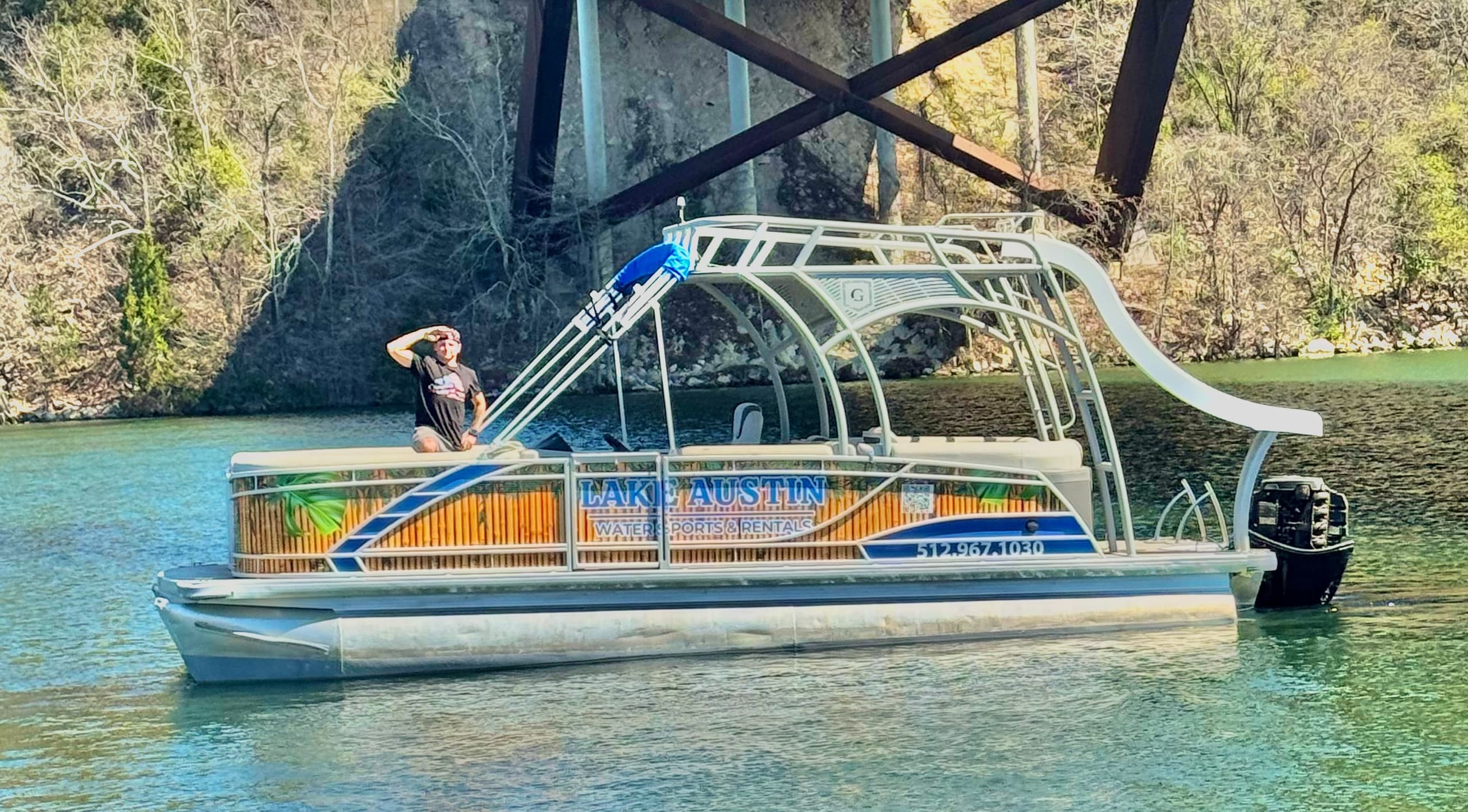 Pontoon party boat anchored on Lake Austin near shoreline