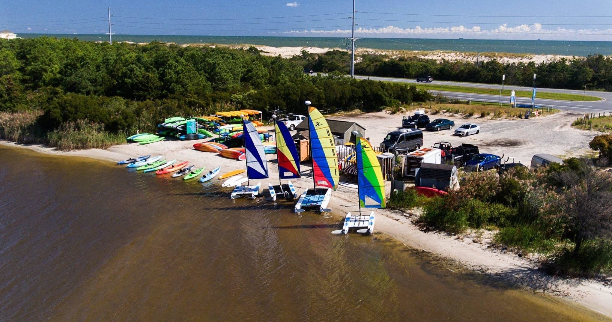 Colorful sailboats and kayaks lined along coastal inlet launch
