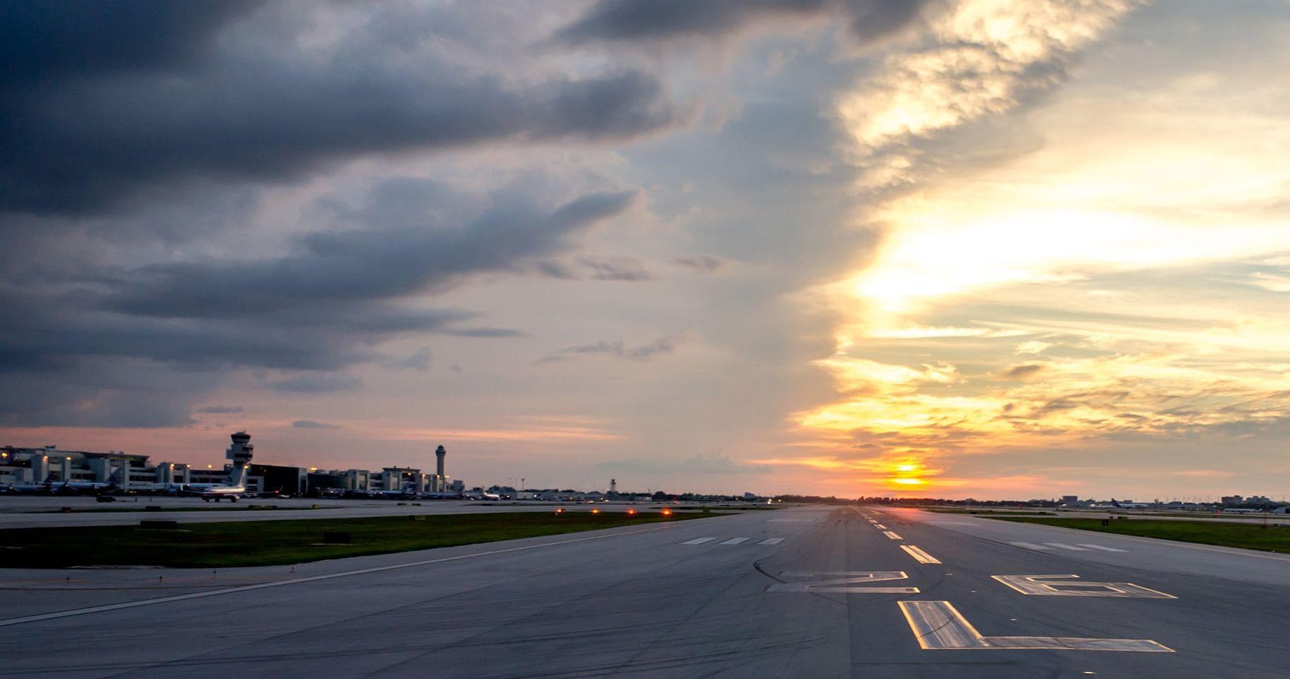 Commercial airplane on runway at sunset with dramatic sky view