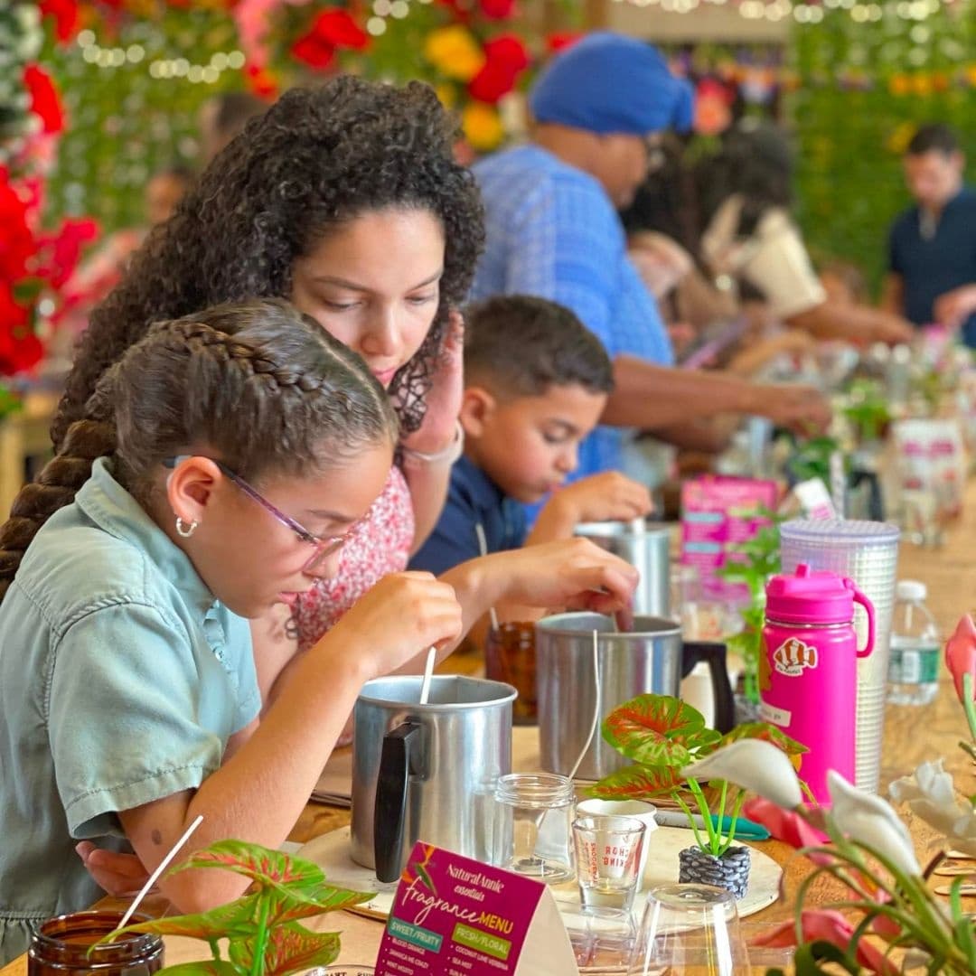 Kids and parents making candles in busy indoor community workshop