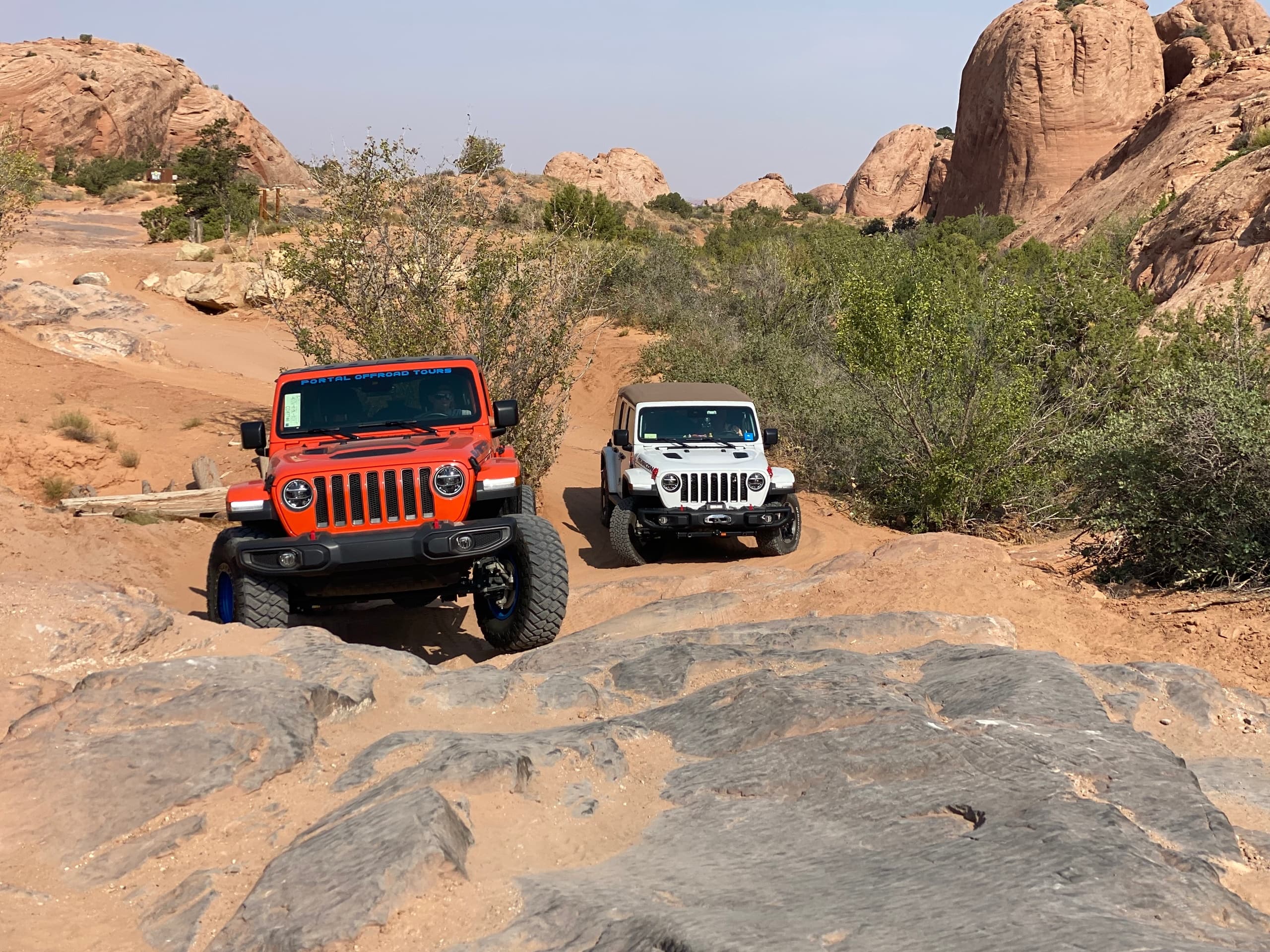 Two Jeeps climbing slickrock trails in red rock desert landscape