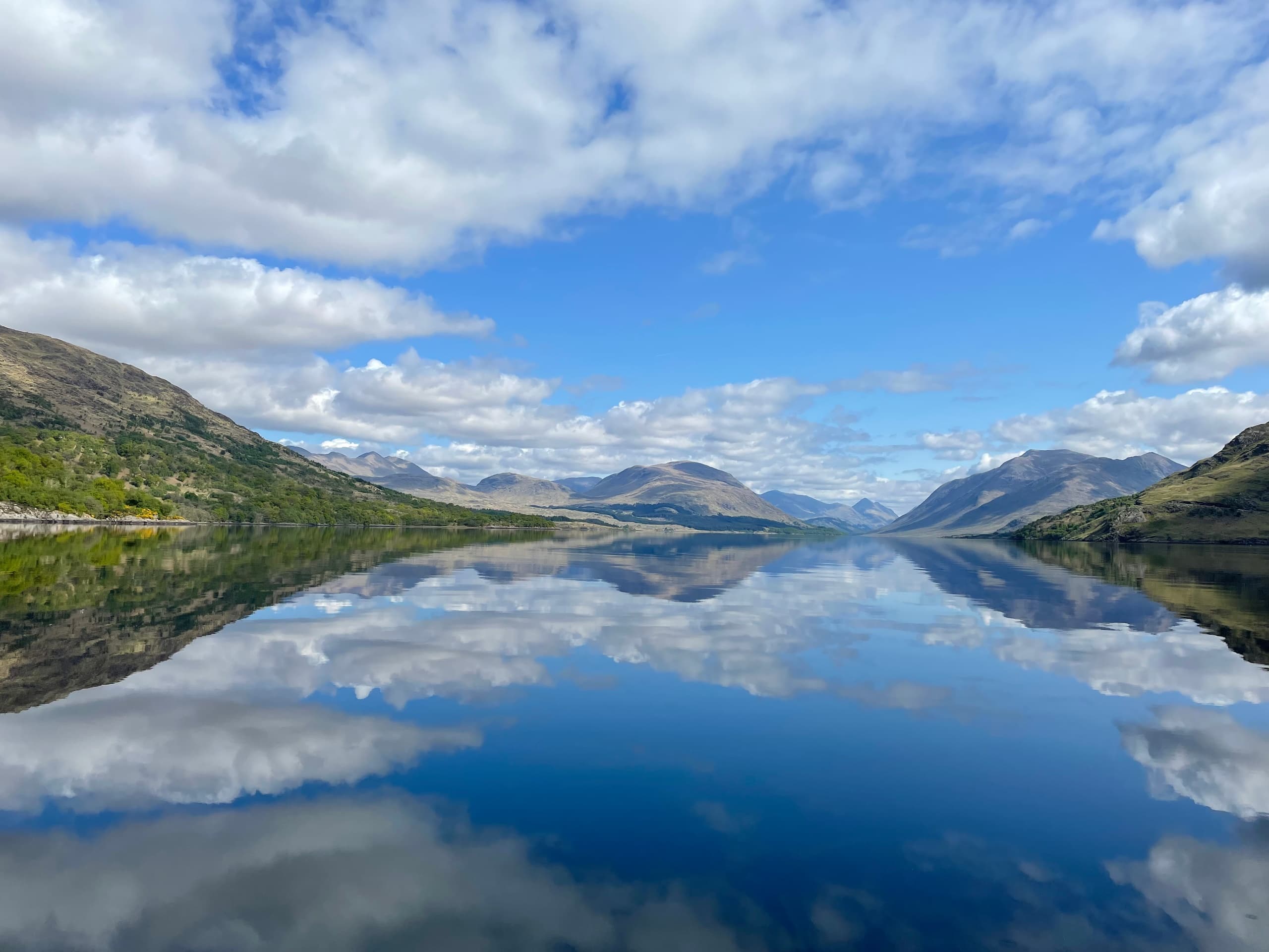 Mirror-like loch reflection with mountains during scenic boat cruise