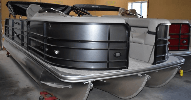 Modern black pontoon boat in indoor marina storage, showroom