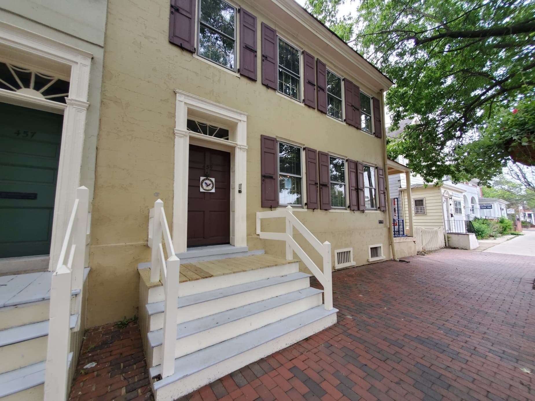 Brick sidewalk and historic townhouse on tree-lined street