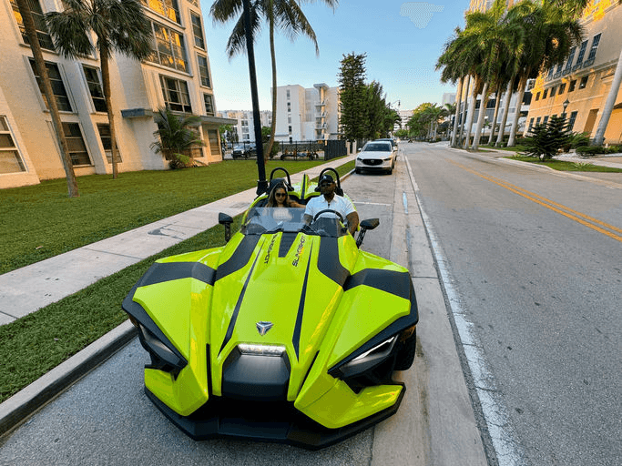 Bright green three-wheeled roadster driving along sunny city street