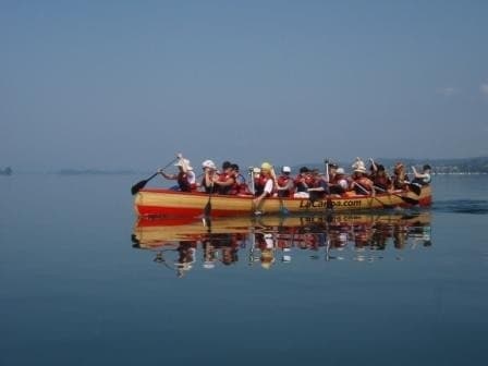 Red canoe gliding on calm Lake Constance with distant hills