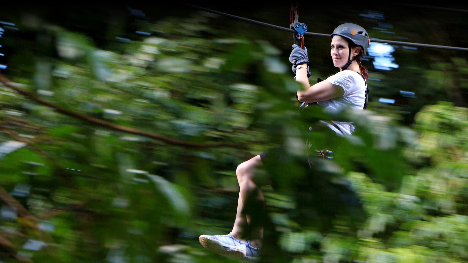 Fast zipline ride with rider flying past dense tropical foliage