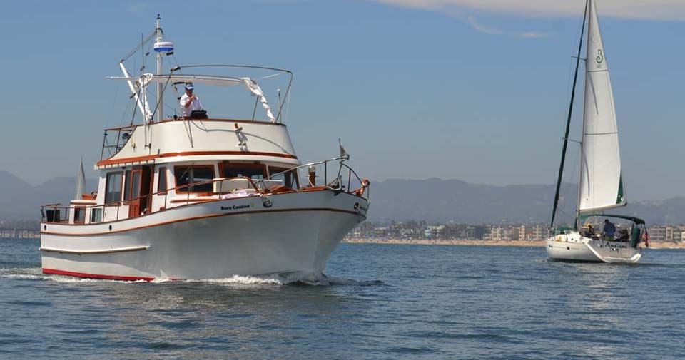 Motor yacht cruising coastal waters at sunny seaside harbor