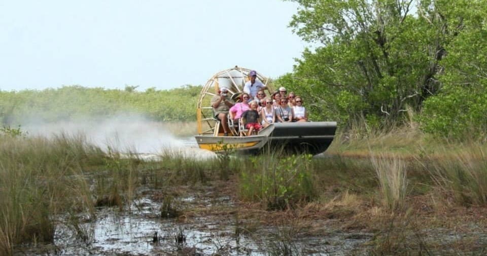 Airboat tour skimming Everglades marsh with passengers