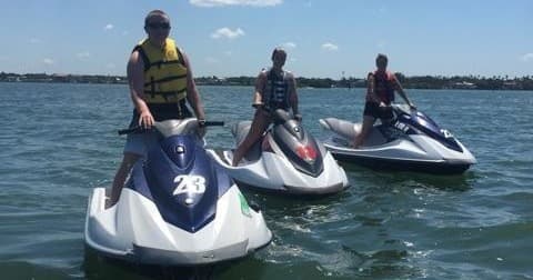 Three waverunners idling on calm bay water with riders