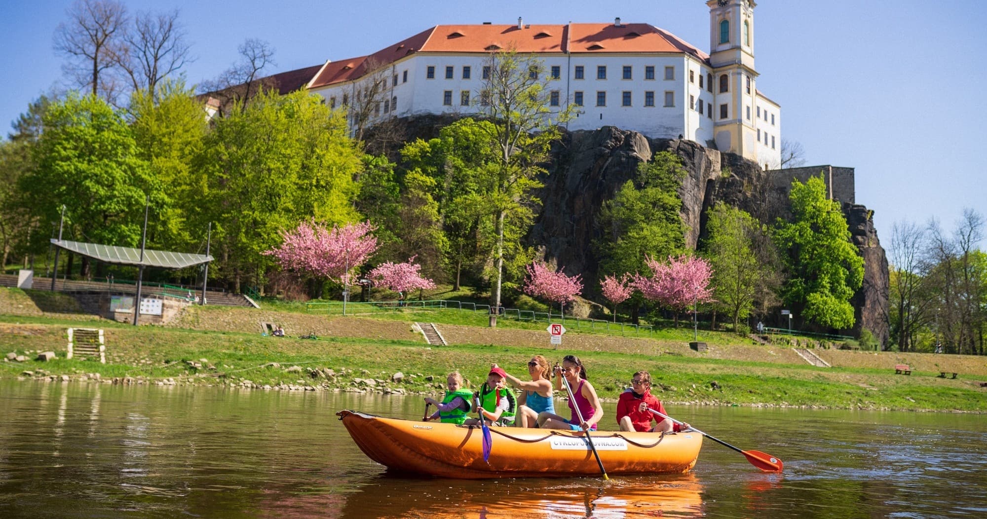 Couple canoeing on wide river under bright blue sky and hills