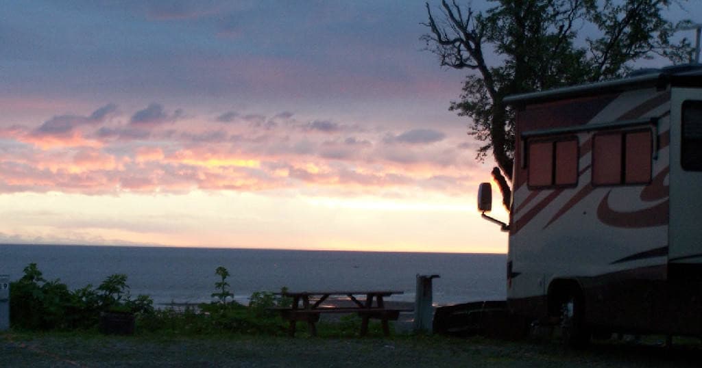 Ocean sunset view with RV campsite and picnic overlooking bay