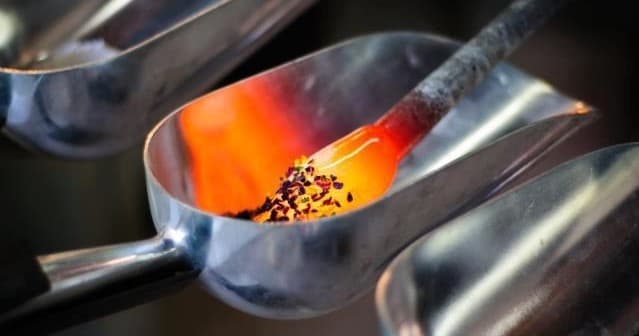 Molten glass and colored frit in scoops during furnace work