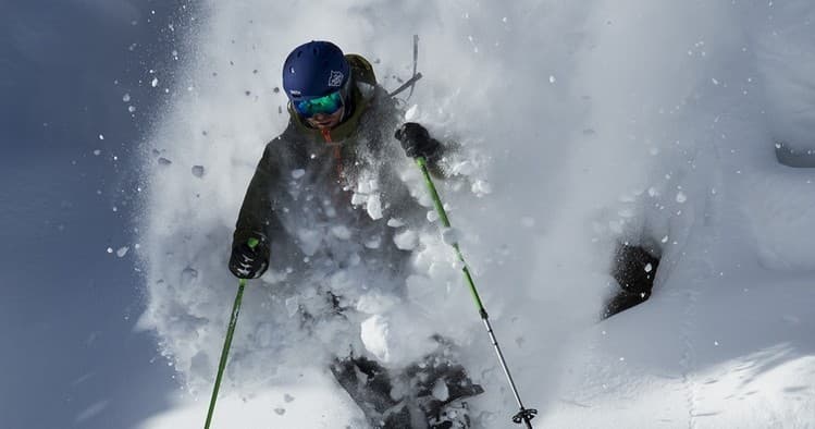 Skier carving through deep powder in alpine backcountry mountain run