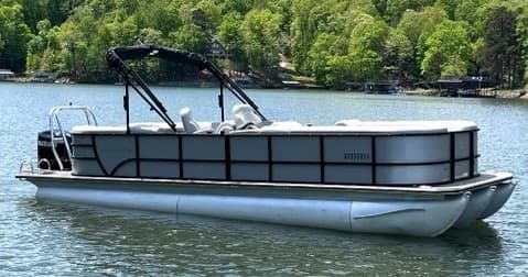 Silver pontoon boat rental cruising tranquil lake near woodland shore