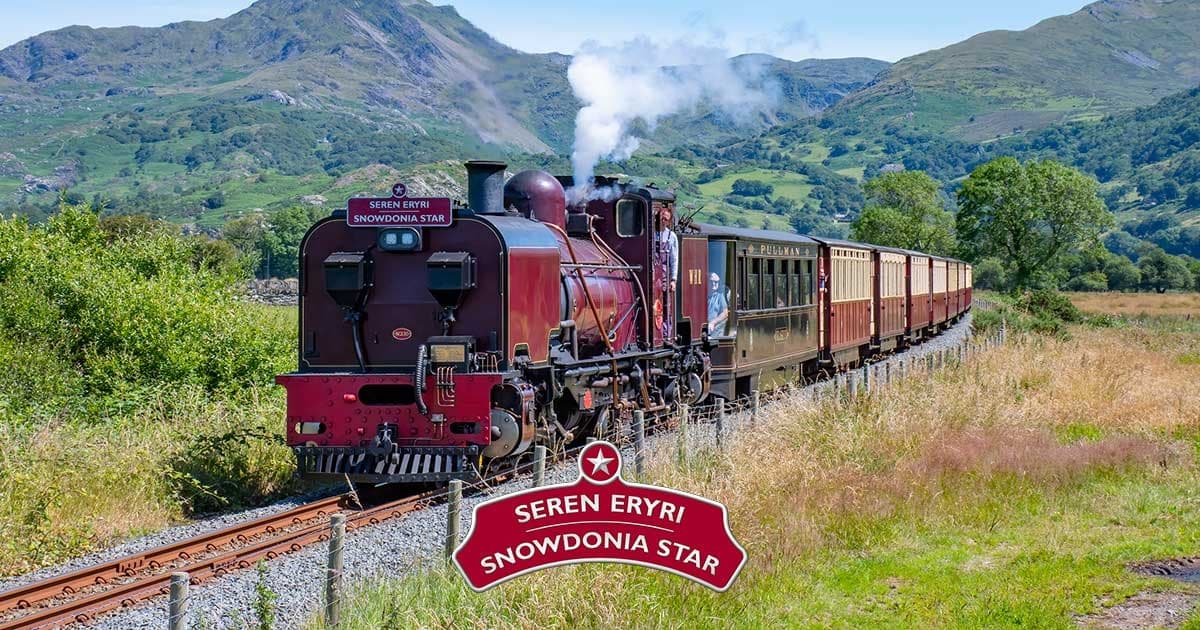 Red steam locomotive traveling through green mountain valley