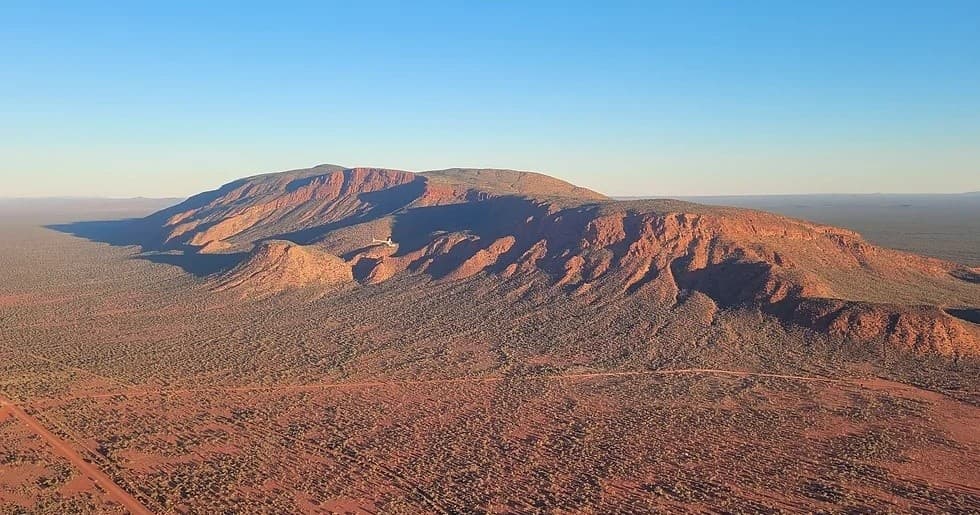 Sunlit rugged mountain range aerial over red outback landscape