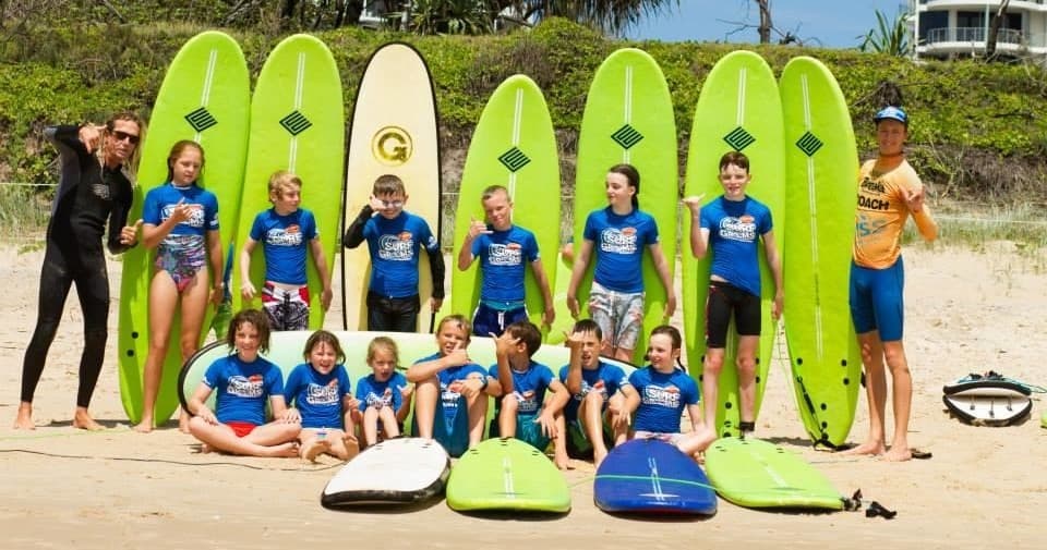 Surf school group with bright surfboards lined up on beach