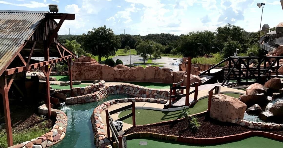 Panoramic mini-golf hole with water stream and wooden bridge