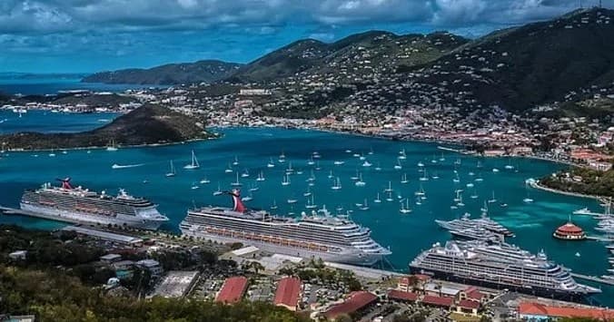 Cruise ships docked in Caribbean harbor by hillside town