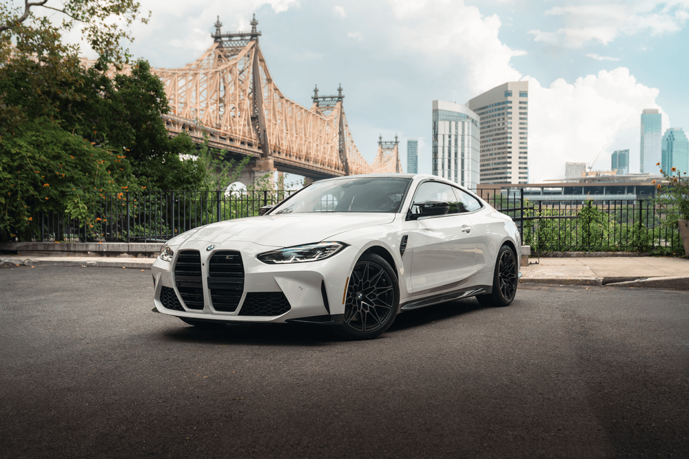White luxury coupe staged beside iconic urban bridge and river