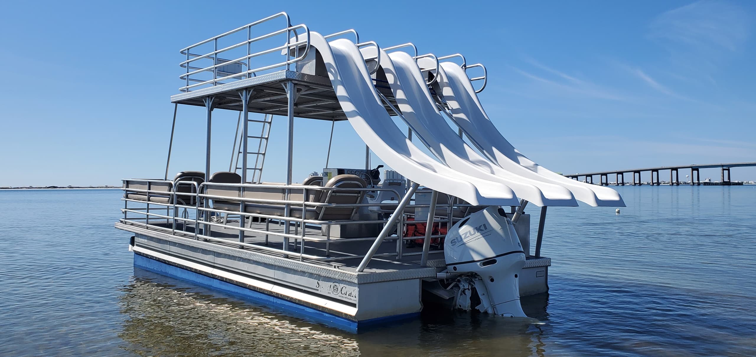 Party pontoon with water slides docked on coastal bay near Navarre Beach