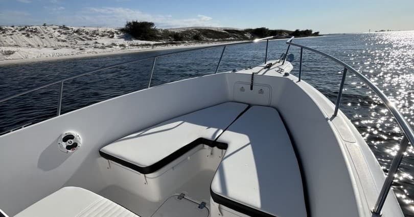 Boat bow cruising along sandy Gulf coast shoreline under sun