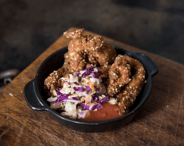 Crispy fried chicken with slaw served in cast-iron skillet