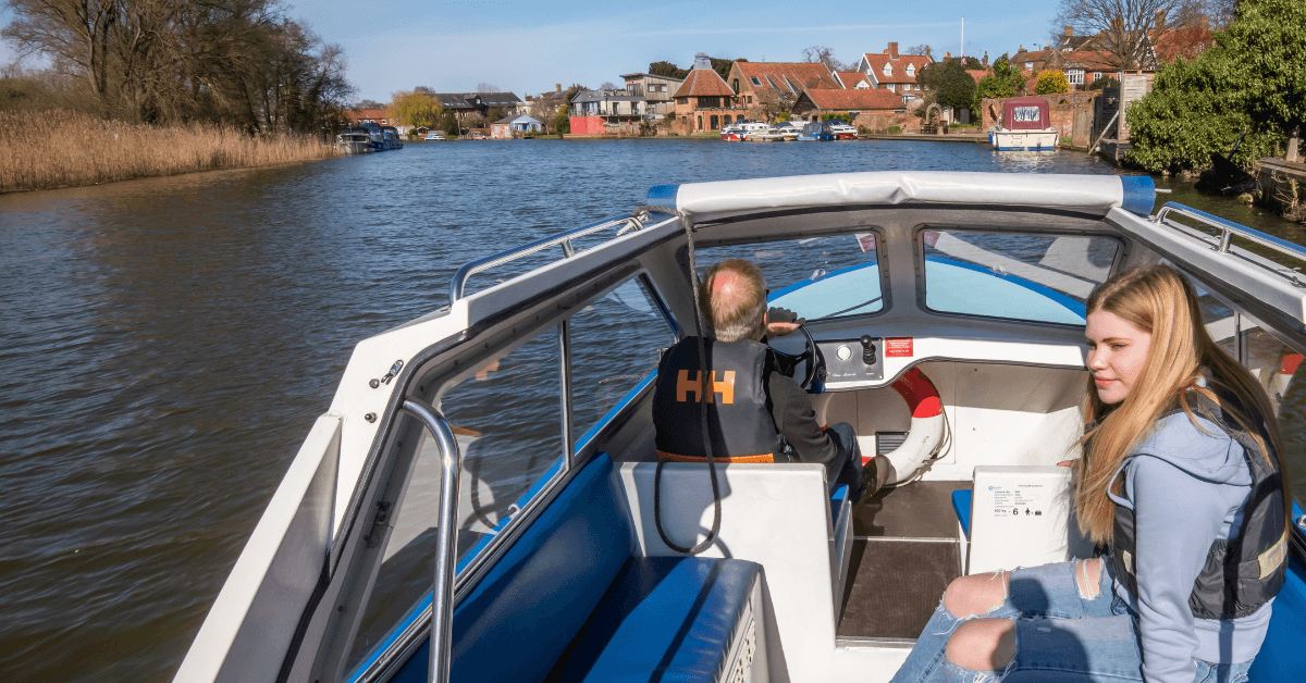 Passengers cruising on river past village houses, scenic boat trip