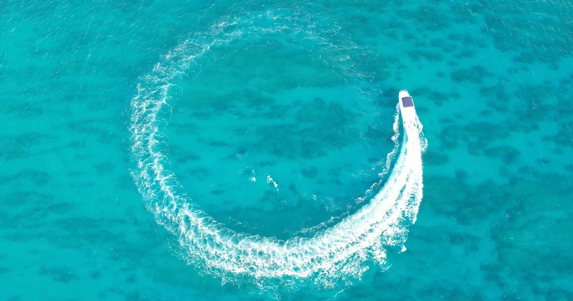 Speedboat carving circular wake in turquoise Hawaiian waters