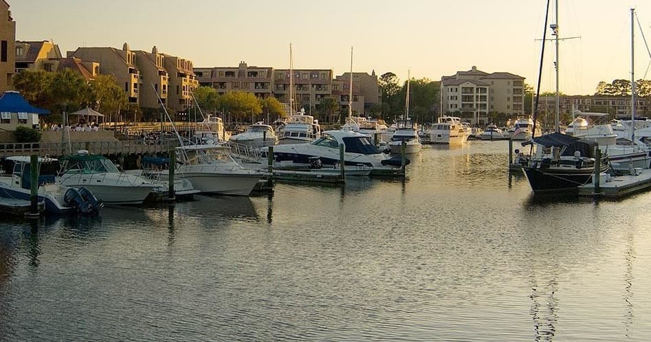 Sunset marina with moored sailboats and calm harbor waterfront