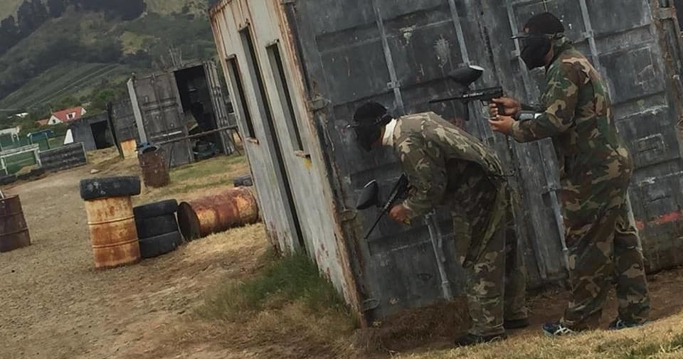 Two paintball players taking cover behind corrugated bunker