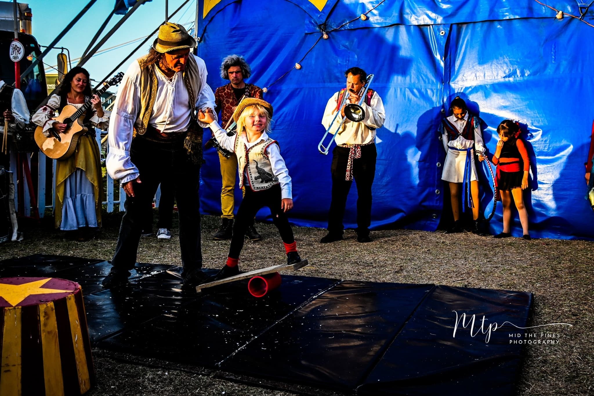 Street performers and musicians entertaining outside blue circus tent