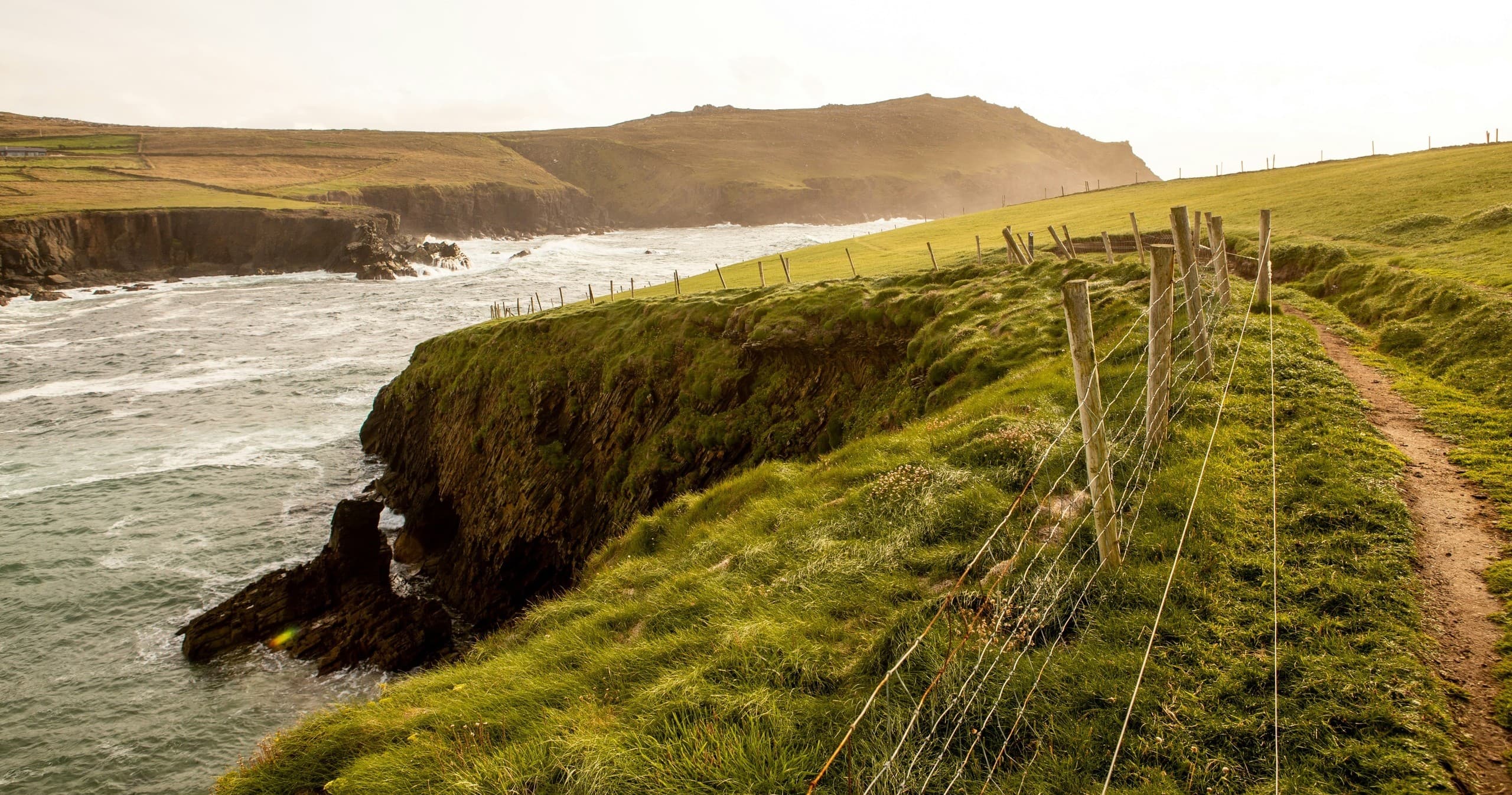 Coastal walking path along grassy cliffs overlooking Atlantic sea