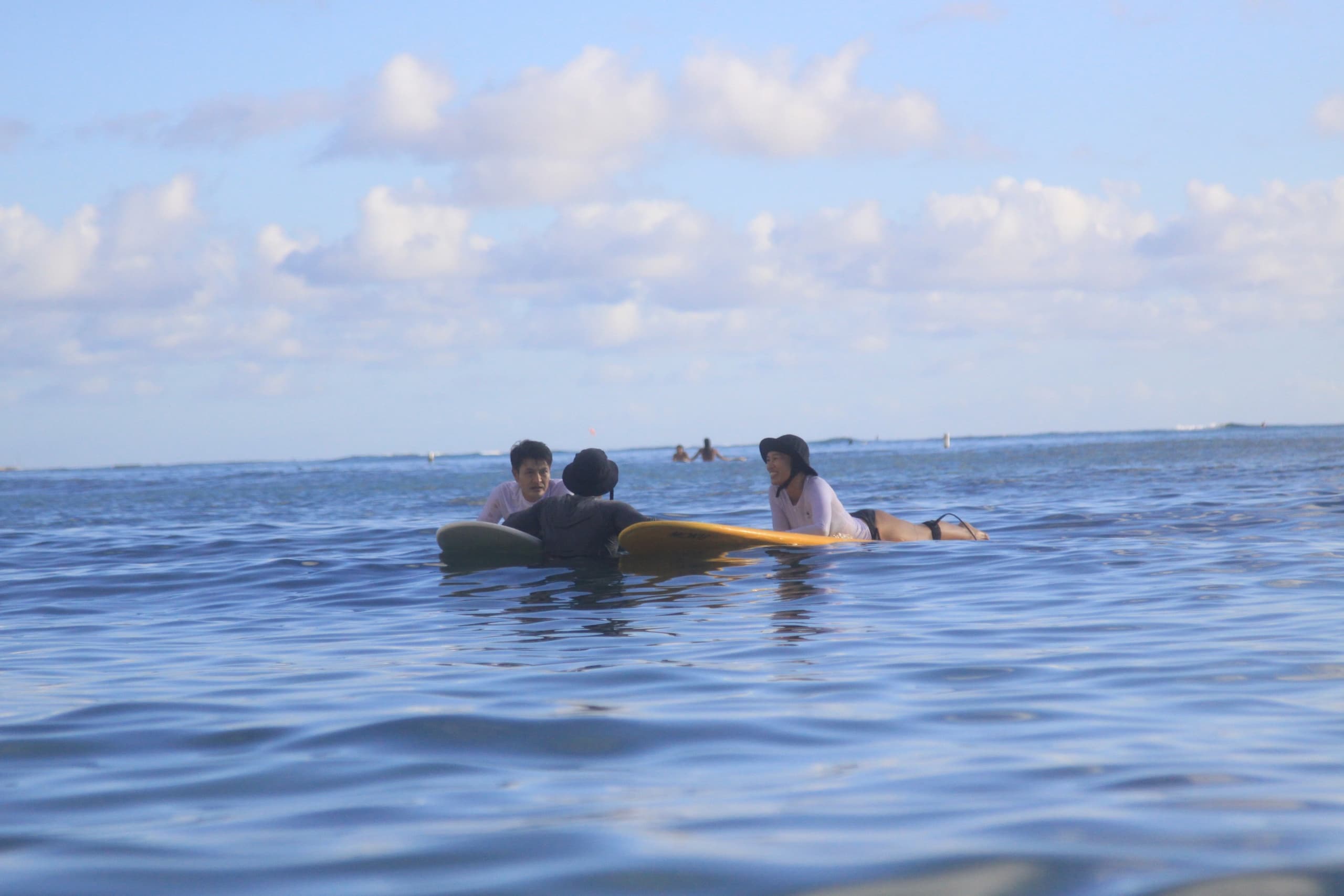 Group on surfboards floating in calm open ocean under clouds