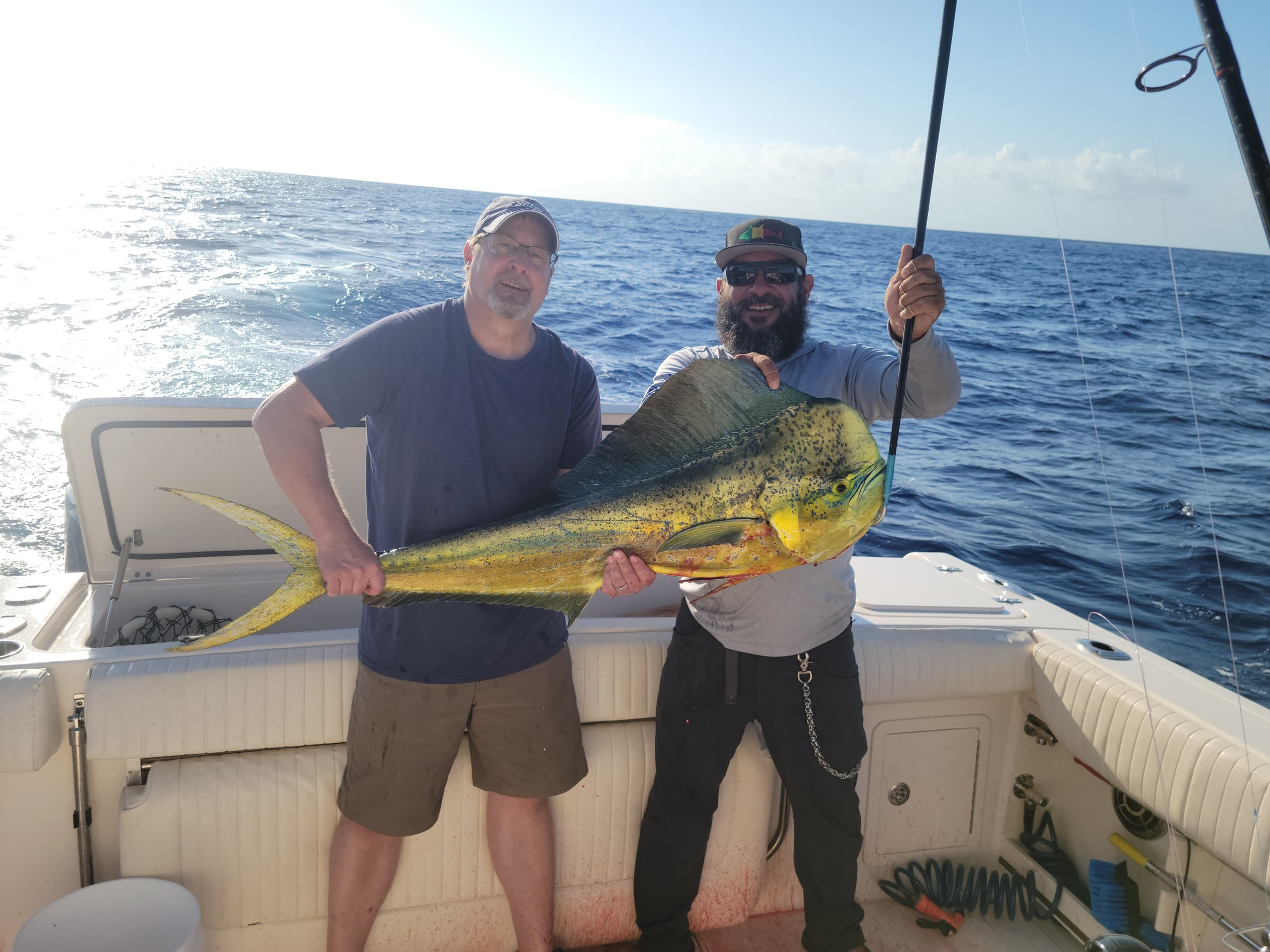Two fishermen displaying large mahi-mahi on an offshore boat