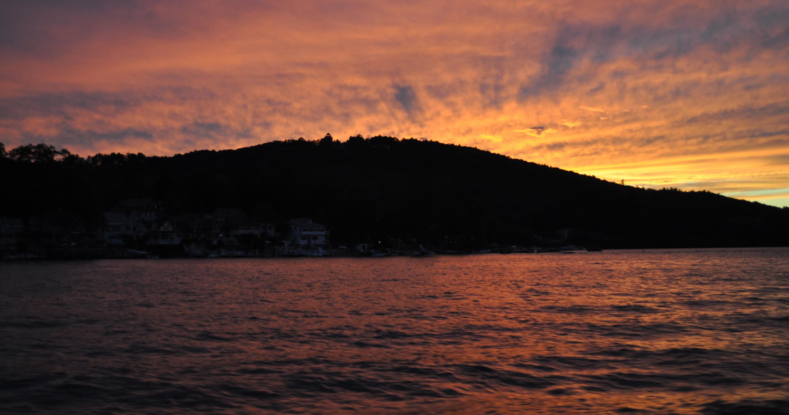 Sunset over lake with silhouetted hills and calm water