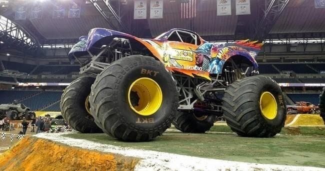 Monster truck performing jumps on stadium dirt track at event