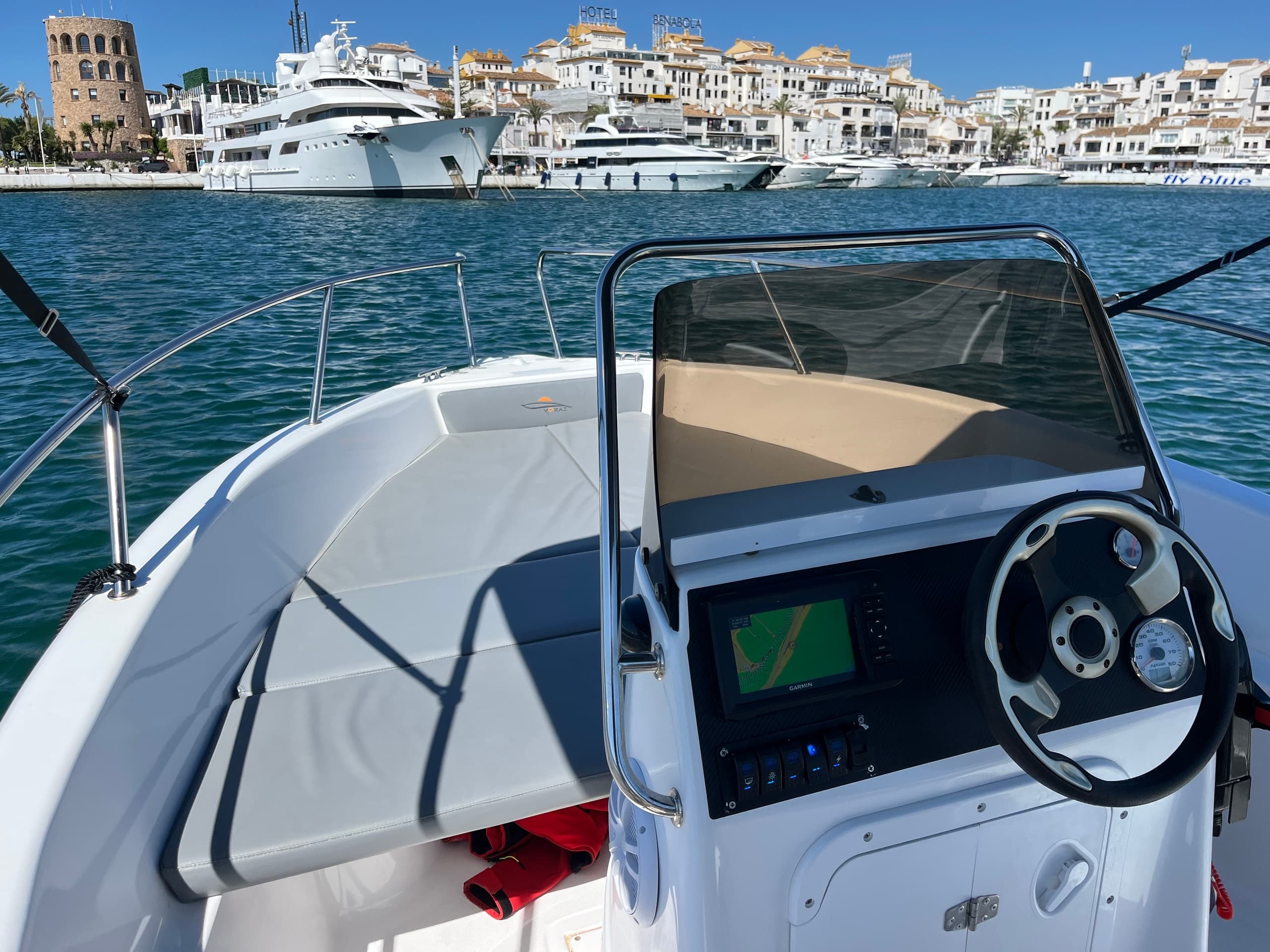 Boat helm view in Málaga marina showing steering and open deck