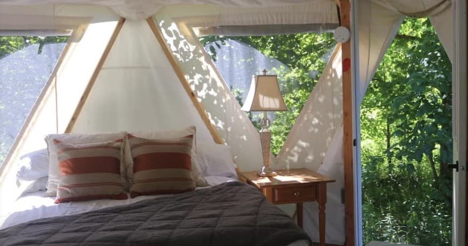 Glamping tent bedroom with forest views at goat farm