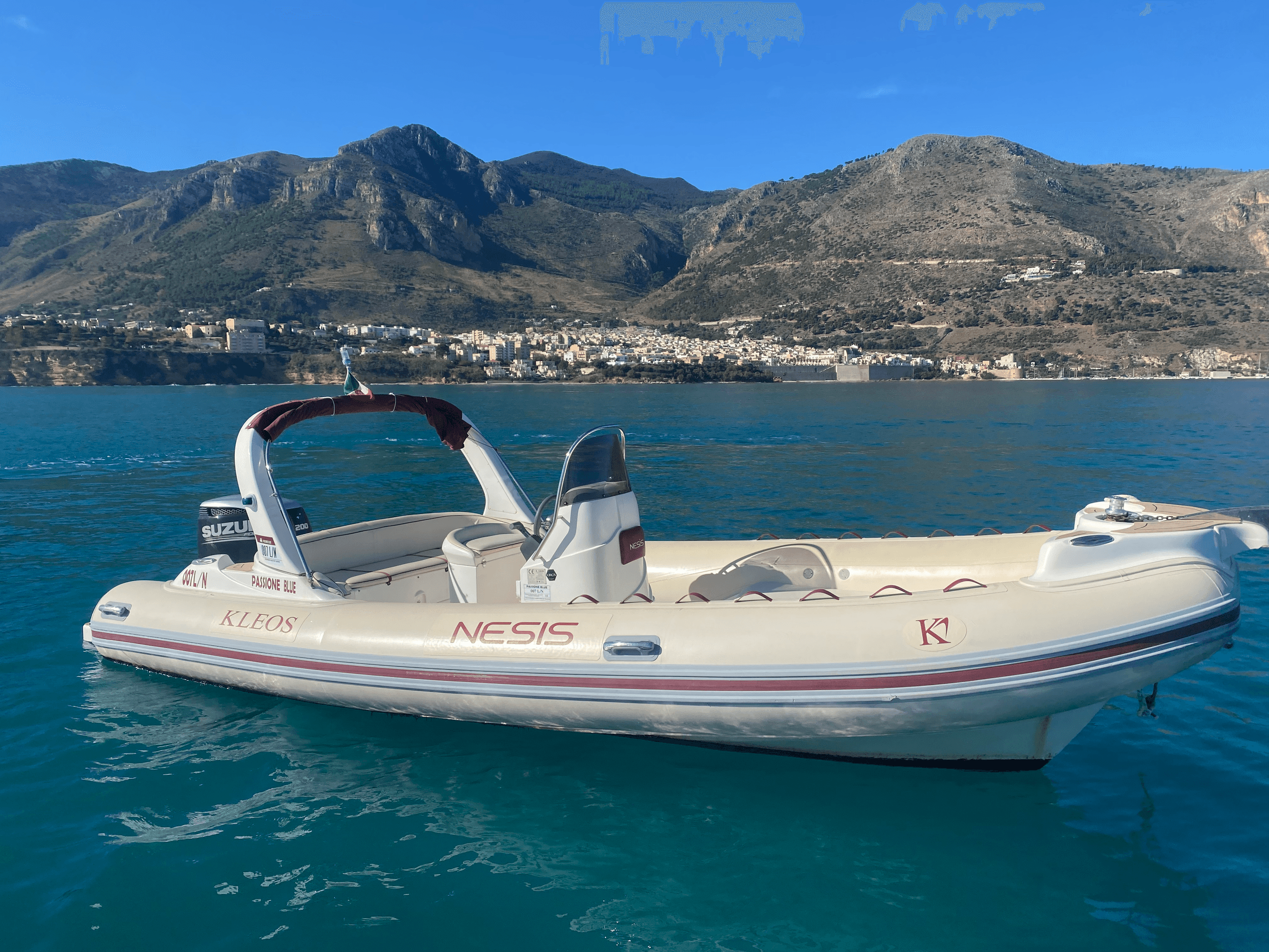 Rigid inflatable boat moored on calm turquoise bay with mountain backdrop