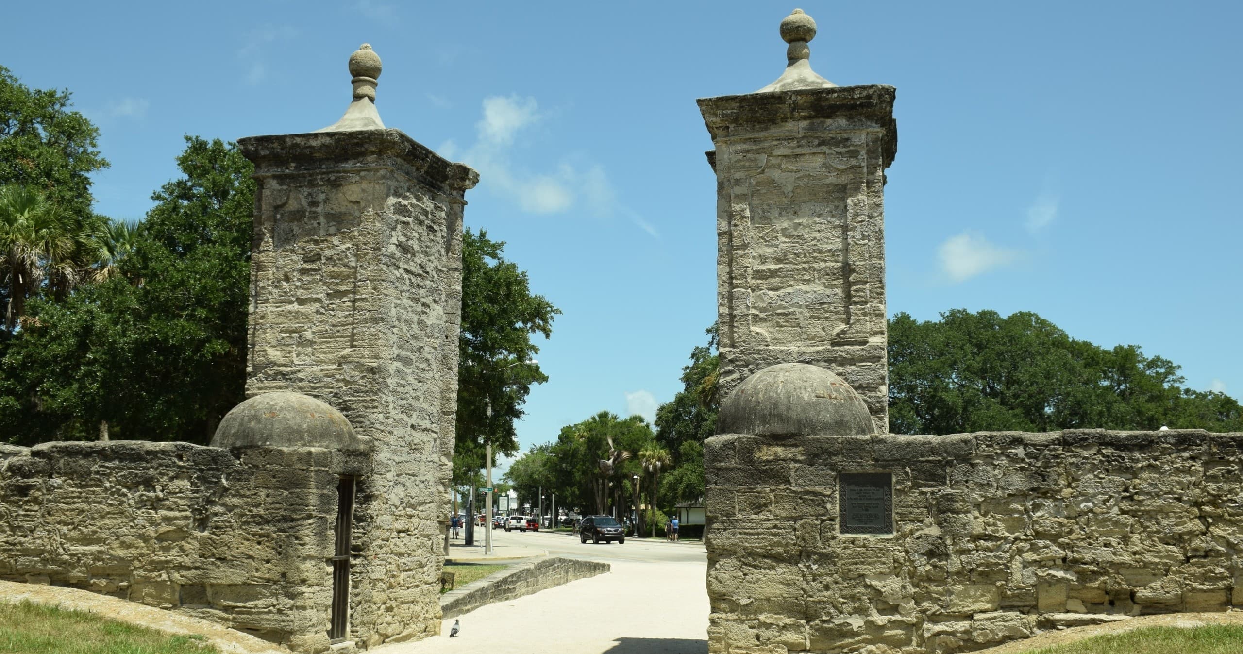 Historic stone gate entrance flanked by pillars at fort city tour
